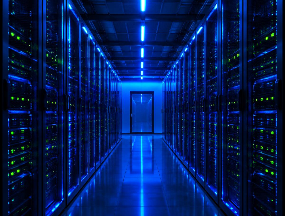 Rows of server racks in a data center lit with blue light